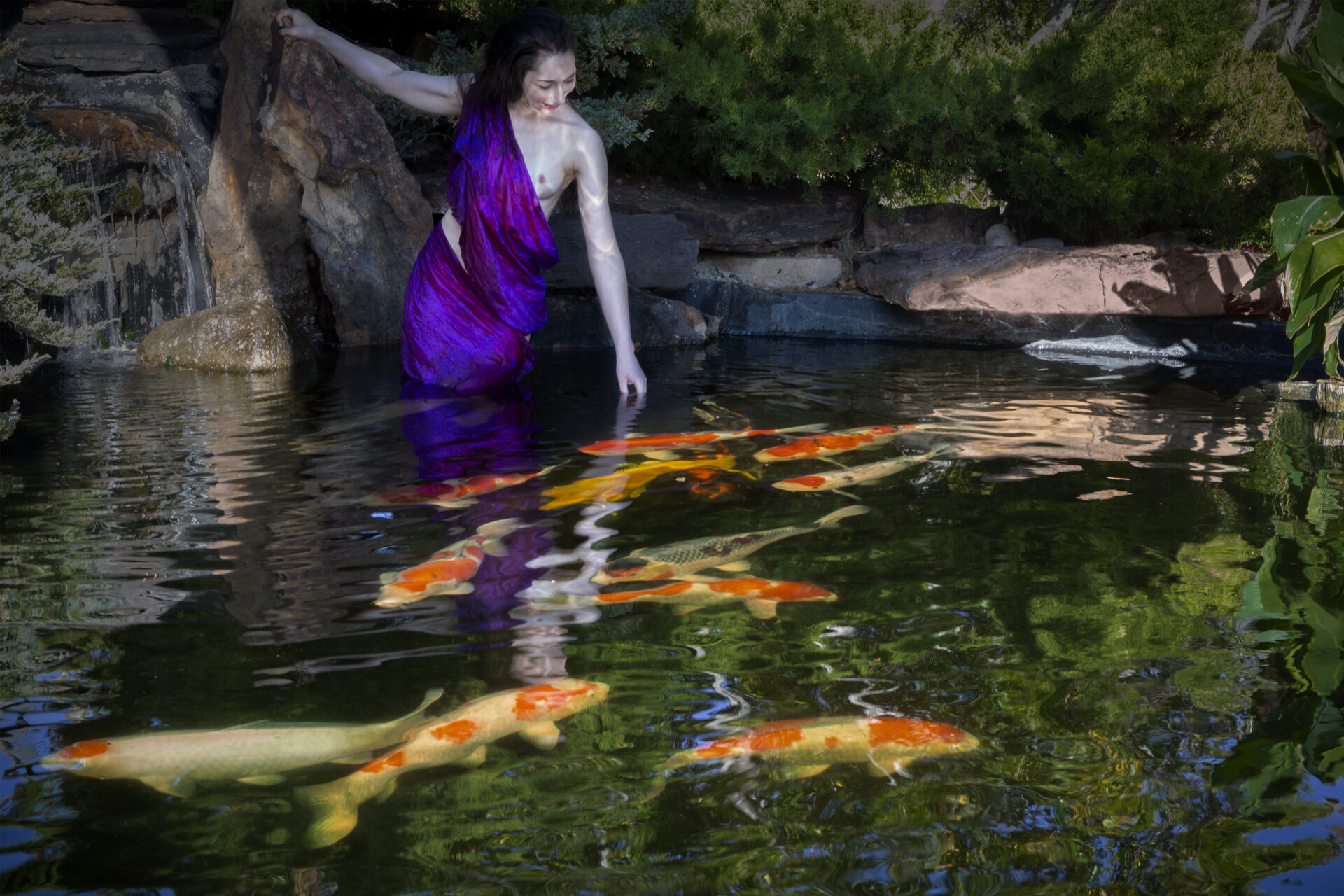 Acasia in a purple robe playing with koi